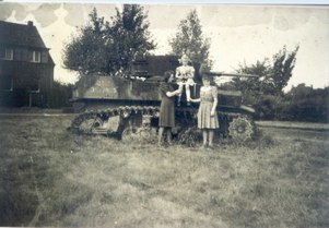 Zwei Frauen und ein Kind vor einem abgeschossenen Panzer