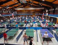 Turnhalle mit Tischtennisplatten und Spielern